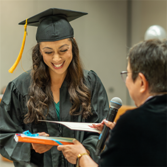 Photo of graduate in cap and gown receiving her GED