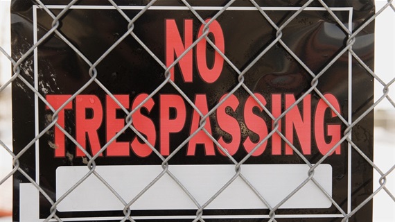 No trespassing sign behind a fence. 